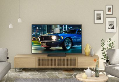 65" Panasonic TX-65HX800E-tv, der viser en blå Ford Mustang fra 1969 parkeret på en livlig gade om natten