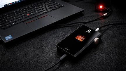 Amplificatore per cuffie portatile EarMen L-Amp II nero con valvola a vista e rotella laterale collegato a un computer portatile