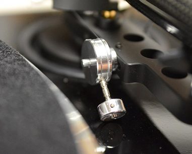 Kromet metaltonarm med pickup og nål, på sort vinylplade, nærbillede set ovenfra