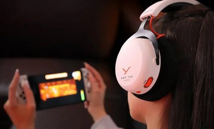 Rear view of head wearing white plastic over-ear headphones with black earpads, orange accents, and a dial on the earcup
