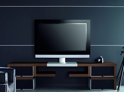 Moderne, designmøbel til TV i mørkt træ og metal med fladskærm, hylder og skuffer, mod mørkeblå baggrund