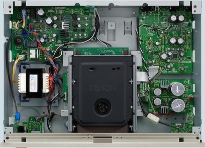 Indvendig i en sort Denon DCD-1510AE CD-afspiller, set ovenfra med låget åbent, hvor de elektroniske kredsløb og komponenter er synlige