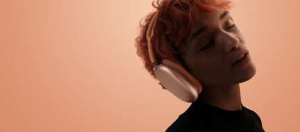 Apple AirPods Max pink headphones worn in profile against a peach background