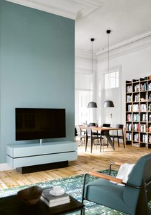 Lav grå TV-møbel, TV-skærm, hvid vægbogreol, træbordplade, grå sofa og lænestol i en moderne stue