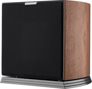 AudioVector RSUB subwoofer i valnød, kabinet i brun valnøddetræ med buede sider, front dækket af sort stofgitter, lagdelt metalsokkel i flere niveauer, set fra højre forfra i trekvart perspektiv