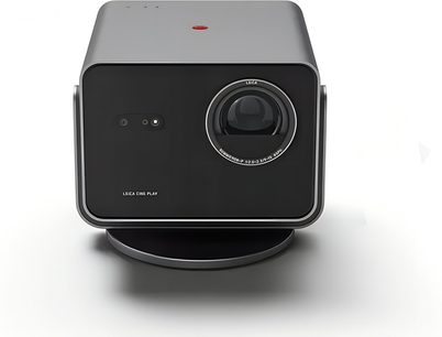 Harmaa Leica Cine Play 1 -projektori mustalla etupaneelilla, etunäkymä, suuri pyöreä objektiivi pyöreän jalustan päällä