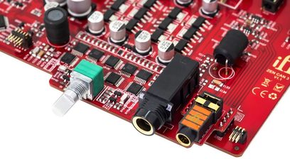 Højkvalitets hovedtelefonforforstærker iFi Audio ZEN CAN 3, set ovenfra, rød printplade, forskellige komponenter, lydstik, sølvfarvet potentiometer, cylindriske kondensatorer, sorte integrerede kredsløb
