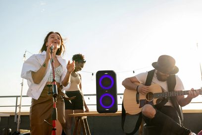 Sort bærbar Bluetooth-højttaler Klipsch GIG XXL mellem to personer, der spiller guitar og synger udendørs