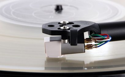 Undersiden af Rega Carbon vinylpladespiller, carbonfiber-tonarm, flerfarvede RCA-kabler, modvægt bagtil