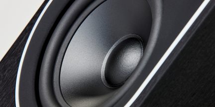Hi-fi regálový reproduktor, detailný záber na matne čierny kužeľ s gumovým závesom v čiernej drevenej ozvučnici