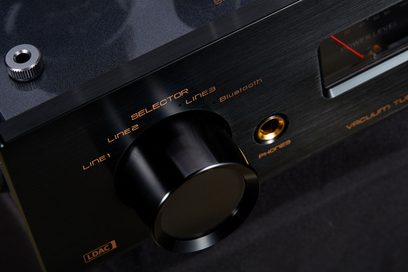 Let frontalt nærbillede i fugleperspektiv af Cayin Jazz 80 EL34 sort, integreret stereo rørforstærker i sort børstet aluminium, med stor cirkulær vælgerknap, gyldne serigrafier og hovedtelefonudgang indrammet i guld