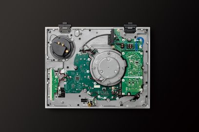 Gramofon Technics SL-1210GMEEK – vnitřní pohled, zelené desky plošných spojů na šedém kovovém šasi, černé pozadí