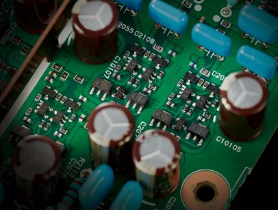 Placă de circuit imprimată verde cu mai mulți condensatori electrolitici și rezistențe montate pe suprafață