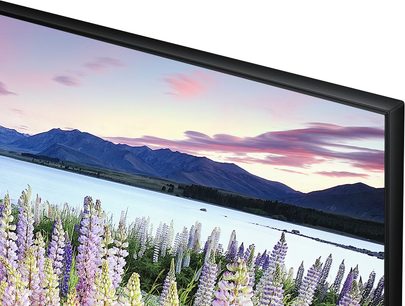Samsung UE32J5500-fjernsyn der viser et snedækket bjerglandskab og en sø med lilla lupiner i forgrunden