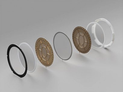 Cinque anelli metallici dorati traforati di diversi diametri, dal più piccolo al più grande, allineati di profilo su uno sfondo grigio uniforme
