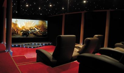 Privati kino salė su plačiaekraniu ekranu, juodos odos foteliais, raudonu kilimu, juodomis sienomis ir apšviestomis žvaigždėmis lubomis