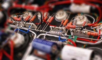 Røde og blå elektroniske komponenter forbundet med ledninger i en metalkabinetboks, tæt på visning