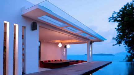 Terrazza di una villa contemporanea bianca con piscina a sfioro e vista mare al crepuscolo
