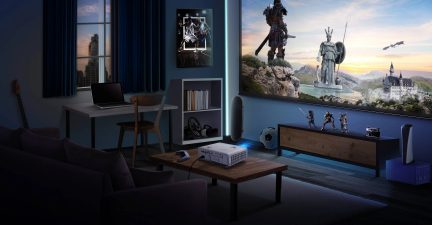 Plat scherm, houten bureau, figuurtjes van personages, projector, luidspreker, in een donkere kamer met uitzicht op een landschap