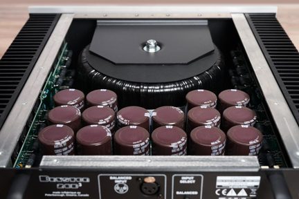 Amplificator de putere Bryston 28B3 deschis, cu un transformator toroidal mare în centru și condensatori maro aliniați