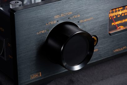 Nærbillede i trekvart vinkel forfra til venstre af Cayin Jazz 80 EL34 sort integreret stereo rørforstærker, front i børstet aluminium med stor sort cirkulær vælger, gylden serigrafi og baggrundsbelyst VU-meter