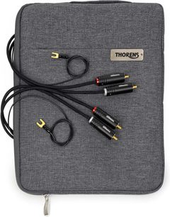Cavo phono Thorens PhonoConnect PHS 150 RCA-RCA nero da 1,5 m con guaina in tessuto intrecciato, connettori RCA neri con indicatori rosso e bianco, spinotti dorati e forcelle di massa gialle, vista dall’alto posato su una custodia in tessuto grigio