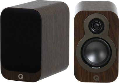 Dvě knihovnové reproduktory Q Acoustics 3010c v ořechovém dřevě hnědé barvy s zaoblenými hranami, pohled zepředu, levý s černou mřížkou a pravý s tmavě šedě orámovaným tweeterem a wooferem