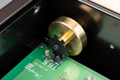 Detailní pohled na vnitřek tuneru Accuphase T-1300, pozlacený mosazný disk, černé ozubené kolo, zelený obvod, šikmý pohled