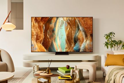 Černý kovový plochý televizor s ultra tenkým rámem, zepředu, umístěný na centrálním obdélníkovém stojanu před bílým televizním nábytkem