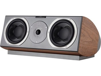 Cassa centrale AudioVector R Center Signature in noce, vista di tre quarti anteriore, finitura in legno di noce e pannello frontale in metallo grigio, due woofer con cornice metallica e tweeter circolare centrale, posizionata su una base coordinata