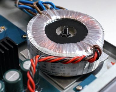 Nuprime DAC-9SE sort audio-DAC-konverter, nærbillede forfra af toroidspolen, røde og blå kabler tilsluttet
