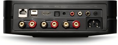 Зблизьте задній план інтегрованого стерео підсилювача BlueSound Powernode 2025 (N331) чорного кольору з матовим металевим корпусом, що демонструє роз'єм LAN RJ45, порт USB-A, HDMI ARC, оптичний/аналоговий вхід, гнізда RCA (ліве-праве) та сабвуфер, роз'єм IR, чотири клемні затискачі для динаміків з червоними або чорними кільцями та роз'єм живлення IEC.