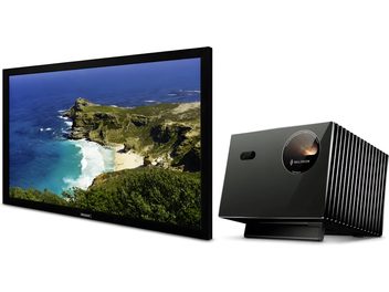 Televisore a schermo piatto nero con paesaggio costiero visualizzato, vista frontale, accompagnato da un proiettore nero con alette laterali