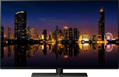 Televizor Panasonic TX-48MZ1500E zobrazující noční výhled na osvětlené mrakodrapy a jejich odraz ve vodě
