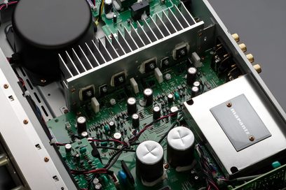 Gümüş altın renkli Marantz PM6007 hi-fi amplifikatörünün iç görüntüsü, yeşil baskılı devre kartı üzerindeki elektronik bileşenleri gösteriyor