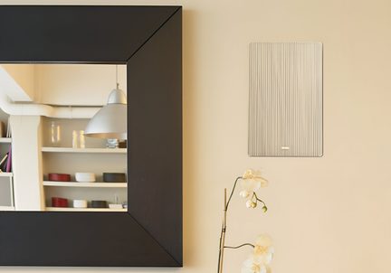 Pannello murale rettangolare beige striato in materiale traslucido, accanto a un grande specchio con cornice nera, vista frontale