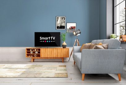 Smart-TV på træmøbel i moderne stue med gråt sofa, lampe, rammer på blå væg og vindue