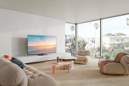 Modern living room with beige sofa, beige armchairs, pink coffee table, wall-mounted TV, gold floor lamp, large windows