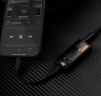 Svart smarttelefon med skjermen på, svart kabel koblet til en gjennomsiktig lydadapter som viser interne kretser