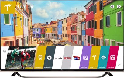 LG 65UF850V-fladskærm viser en grænseflade med apps og et billede af farverige huse ved vandet og fodboldspillere
