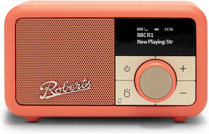 Rádio Roberts Revival Petite 2, oranžový texturovaný plastový kryt s velkým perforovaným mřížkovým reproduktorem a kovovým logem vlevo, černý displej, zlatý ovládací panel a centrální otočný knoflík vpravo, pohled zepředu