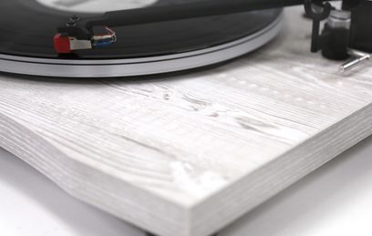 Toca-discos New Horizon 129 branco, vista aproximada do prato de madeira clara com sulcos concêntricos e braço de leitura preto