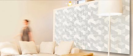 Pannello murale decorativo bianco con motivo geometrico perforato, divano beige con cuscini, persona sfocata sullo sfondo