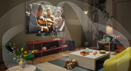 Perspektívás nézet egy nappali szobából, ahol a falon nagy, fekete, üveglapú, lapos képernyős tévé és alatta fekete műanyag hangszórósáv látható. Átlátszó ívek szimulálják a hangterjedést a színes bútorok és a csempézett dohányzóasztal körül.