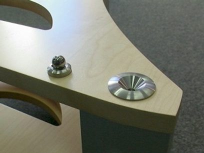 Light wood shelf with two circular cavities containing round metallic objects, close-up top view