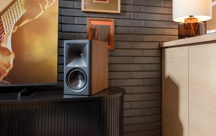 Klipsch Regallautsprecher aus Walnussholz, graue Front mit Horn und Woofer, neben einem Fernseher platziert