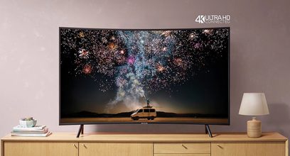 Televizor Samsung UE55RU7305 4K Ultra HD zobrazující barevný ohňostroj nad dodávkou zaparkovanou v poušti v noci