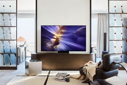Stueinteriør, sort fladskærms-tv set forfra, sort læderchaise longue, skillevægge af struktureret glas