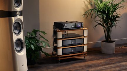 Mebel hi-fi z drewna i metalu, półki ze szkła czarnego, czarne komponenty z kolorowym ekranem i pokrętłem, widok z trzech czwartych