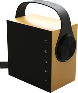Altavoz bluetooth portátil Morel Biggie, carcasa cúbica de plástico bicolor en negro mate y amarillo dorado, vista en tres cuartos desde el frente derecho con ligera inclinación, equipada con una gran rueda lateral negra brillante, un asa arqueada negra y unos iconos blancos alineados verticalmente en la parte frontal.